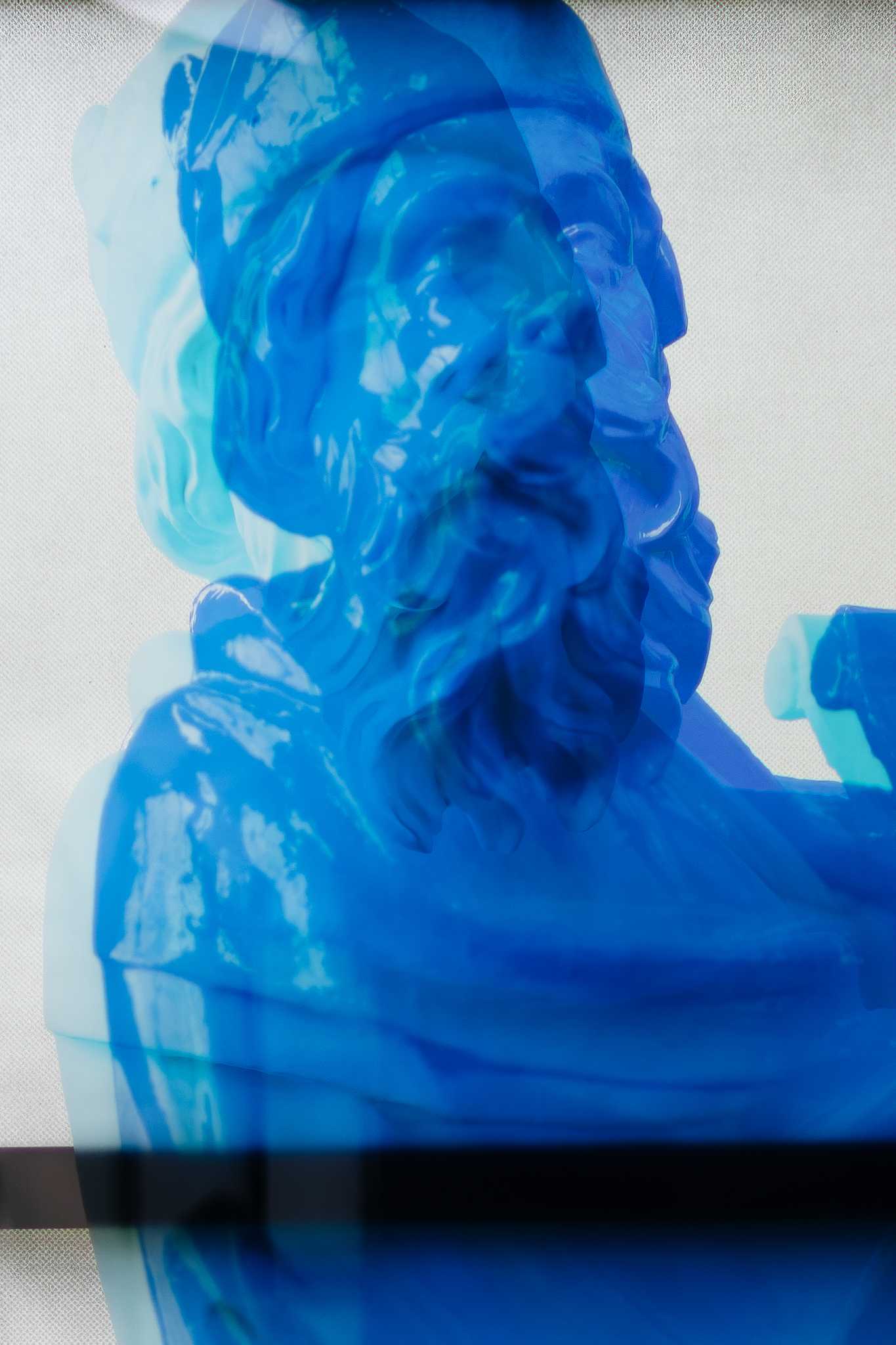 The same print close up: the blue prophet on the window glass, his contours doubled where the layers overlap, a dark glazing bar crossing below.