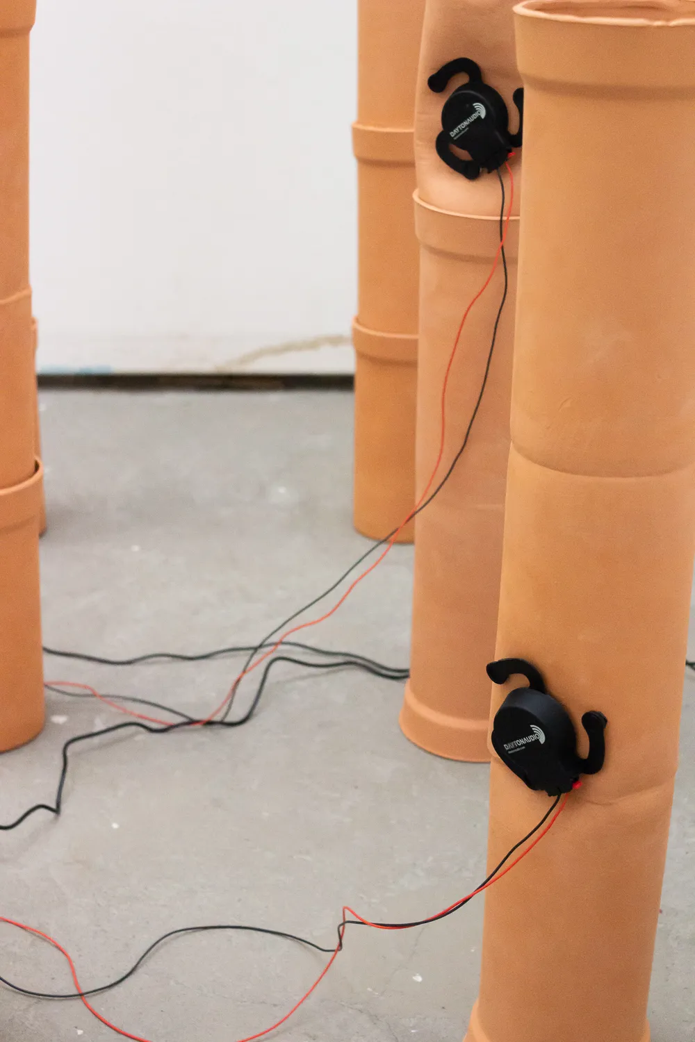 A closeup of a couple of pipes lined up with audio exciters attached.