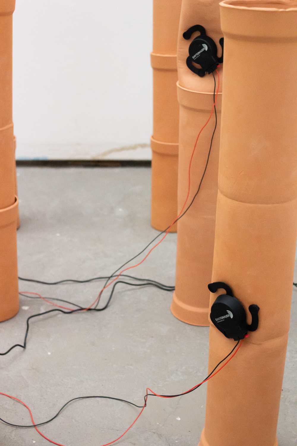 A closeup of a couple of pipes lined up with audio exciters attached.