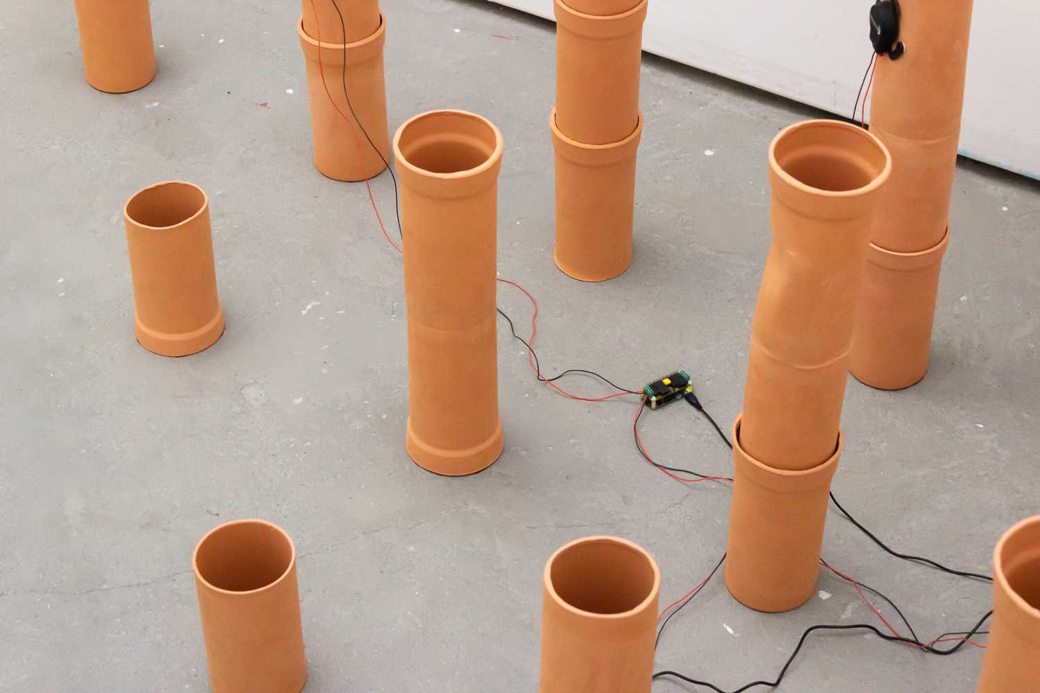 An overhead view of the arrangement of ceramic pipes, showing the wires running into a small electronic device on the floor.