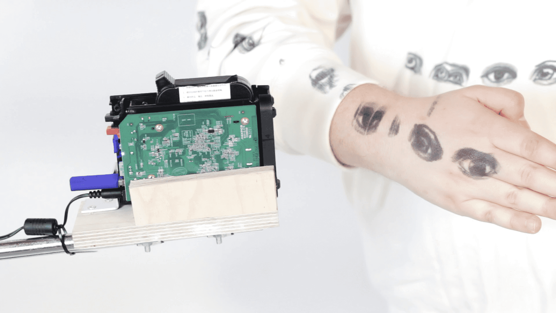 A handheld printer printing eyes onto a person's arm